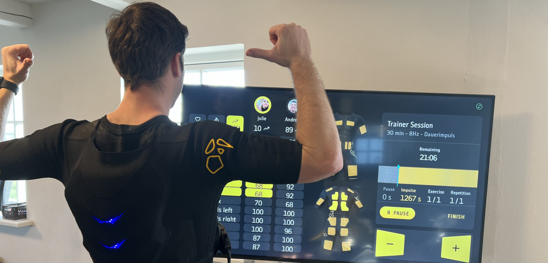 Mand træner med EMS-dragt foran skærm